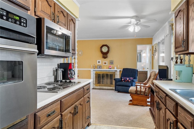 kitchen with decorative backsplash, ornamental molding, stainless steel appliances, and light carpet