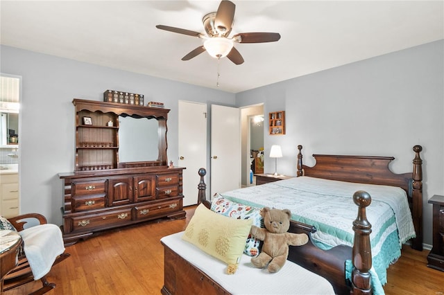 bedroom with ceiling fan, ensuite bath, and light hardwood / wood-style flooring