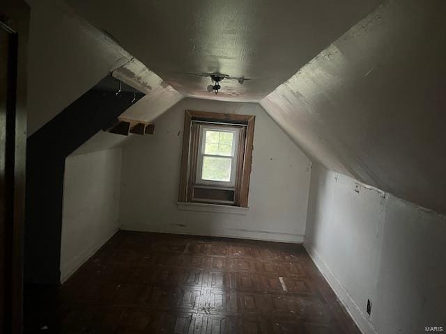 additional living space featuring dark parquet flooring and vaulted ceiling