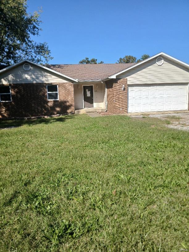 ranch-style house with a garage and a front lawn