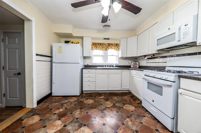 kitchen featuring dark countertops, white appliances, white cabinetry, and a sink