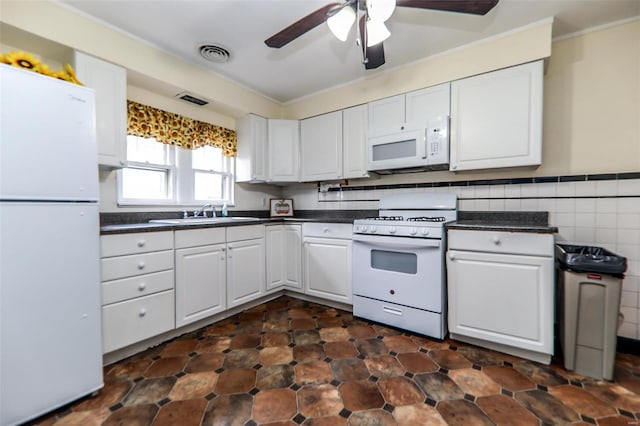 kitchen with dark countertops, visible vents, white cabinetry, a sink, and white appliances