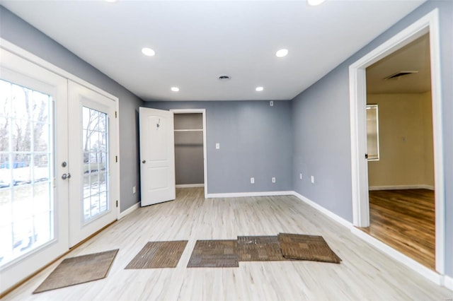 spare room with light wood-type flooring, french doors, visible vents, and a healthy amount of sunlight