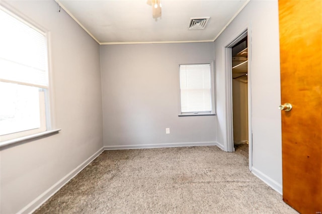 unfurnished bedroom with baseboards, visible vents, light colored carpet, ornamental molding, and a closet