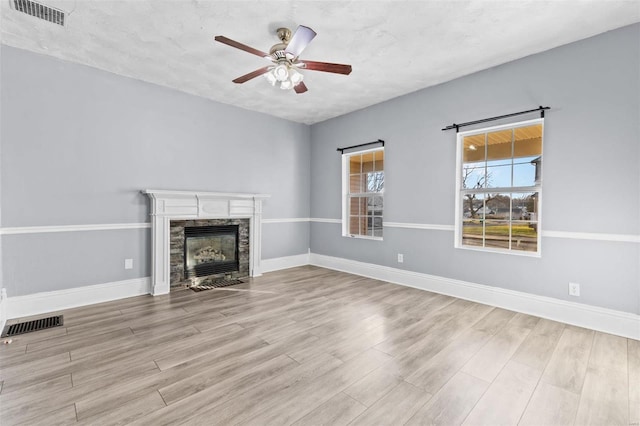 unfurnished living room with a fireplace, a textured ceiling, light hardwood / wood-style flooring, and ceiling fan