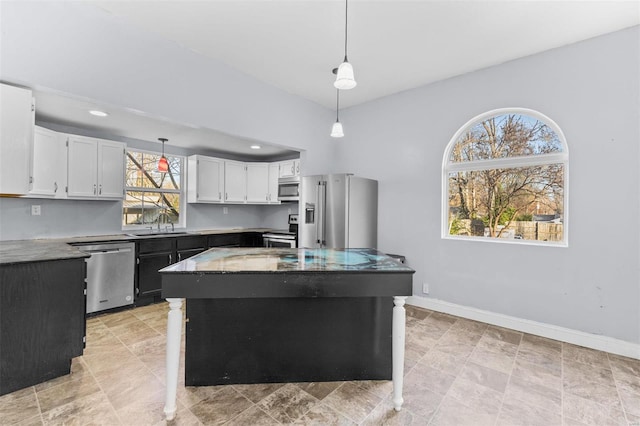 kitchen with plenty of natural light, a kitchen island, white cabinetry, and appliances with stainless steel finishes