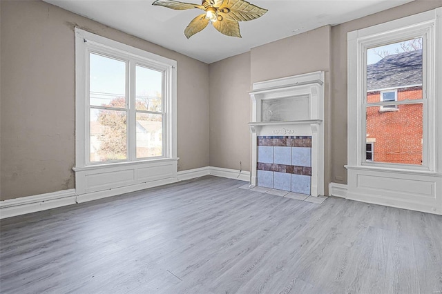 unfurnished living room featuring ceiling fan, light hardwood / wood-style floors, and a wealth of natural light