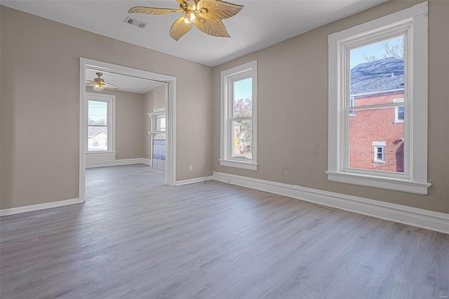 unfurnished room featuring ceiling fan, light hardwood / wood-style flooring, and a healthy amount of sunlight