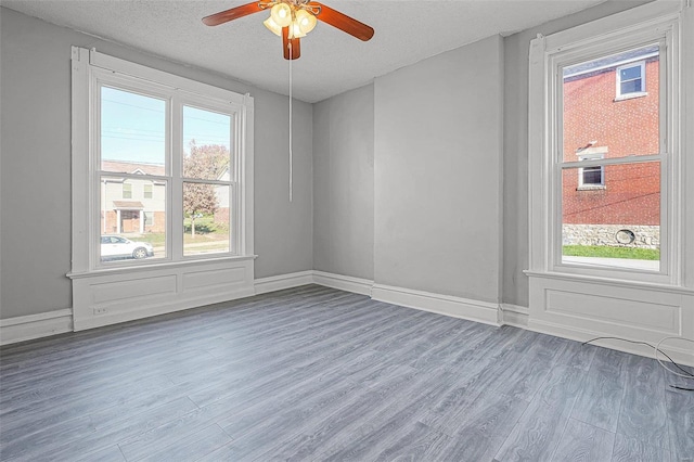 unfurnished room with hardwood / wood-style flooring, ceiling fan, and a textured ceiling