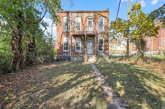 italianate-style house featuring central AC unit, a balcony, and a front lawn