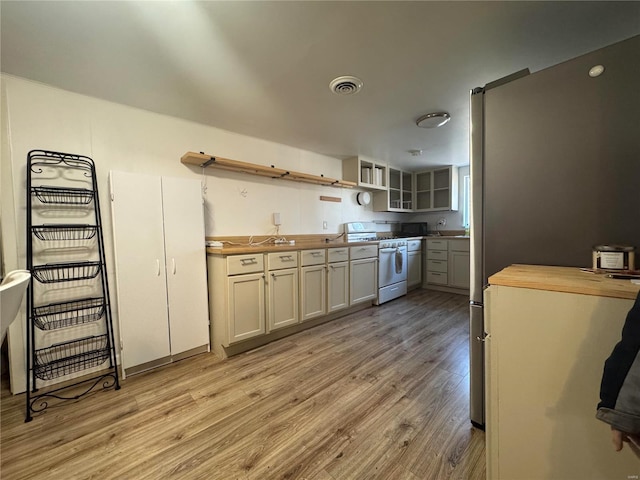 kitchen featuring wood counters, light wood-type flooring, white cabinetry, and stainless steel range oven