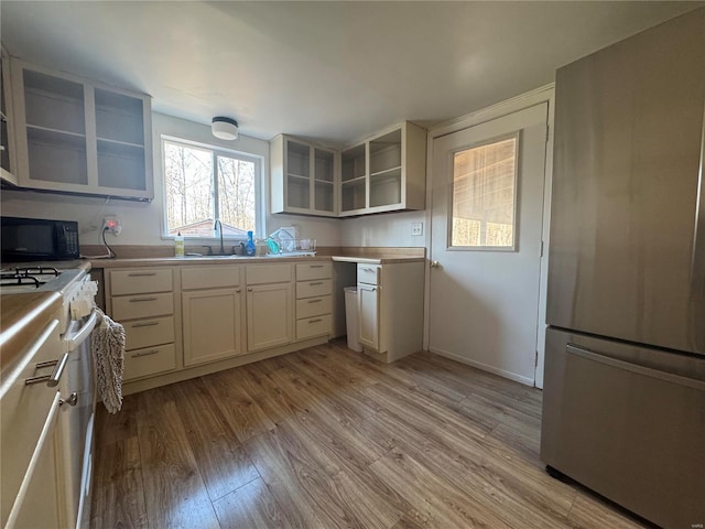 kitchen featuring stainless steel fridge, light wood-type flooring, sink, and range