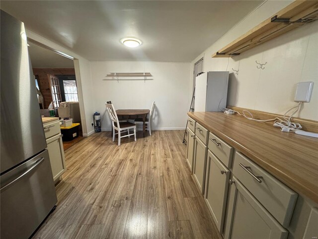 kitchen featuring wood counters, stainless steel fridge, gray cabinets, and light wood-type flooring