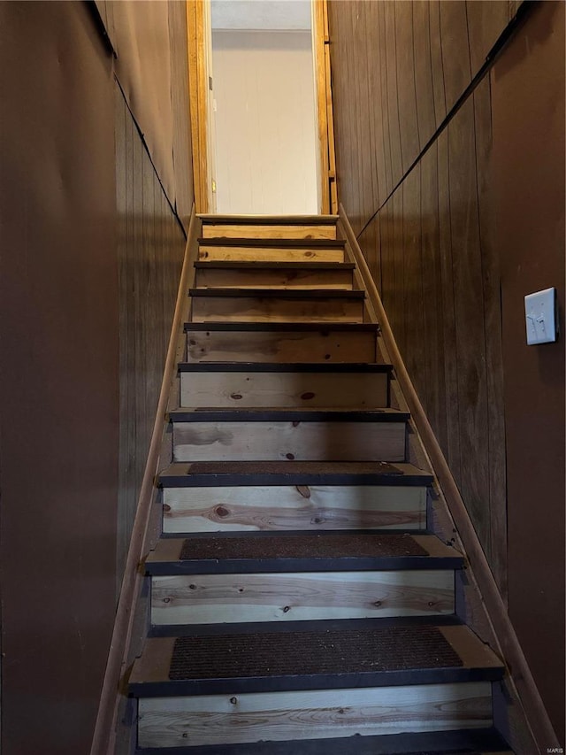 stairs featuring wood walls