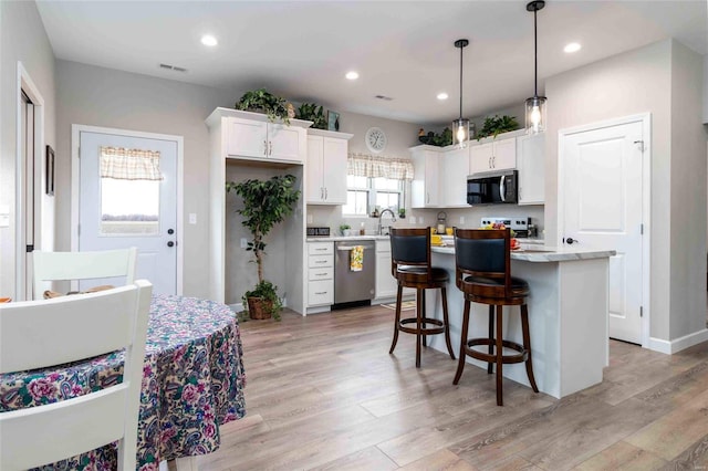 kitchen featuring appliances with stainless steel finishes, white cabinetry, pendant lighting, and a center island