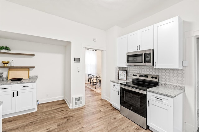 kitchen featuring appliances with stainless steel finishes, light wood-type flooring, white cabinetry, and backsplash