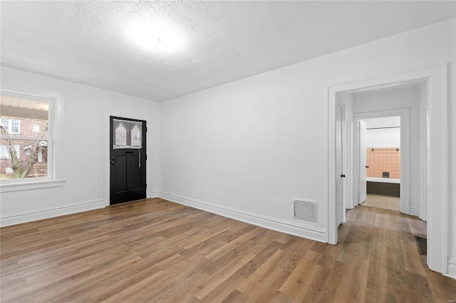 unfurnished room with light hardwood / wood-style floors and a textured ceiling