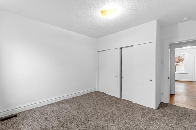 unfurnished bedroom featuring carpet flooring, a textured ceiling, and a closet