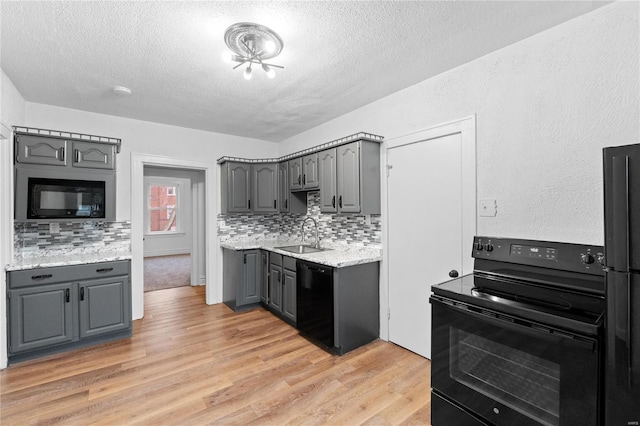 kitchen with gray cabinetry, decorative backsplash, sink, and black appliances