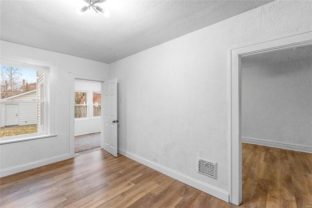 unfurnished room with wood-type flooring and a textured ceiling