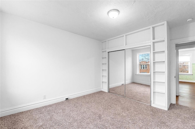 unfurnished bedroom featuring carpet flooring, a textured ceiling, and a closet