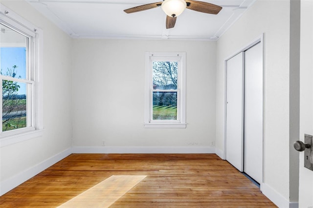 unfurnished bedroom with ceiling fan, light hardwood / wood-style floors, crown molding, and a closet