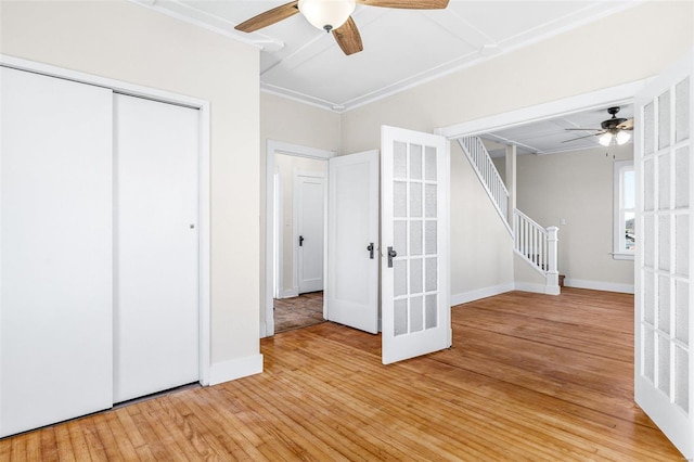 unfurnished bedroom featuring ceiling fan, french doors, light hardwood / wood-style flooring, crown molding, and a closet