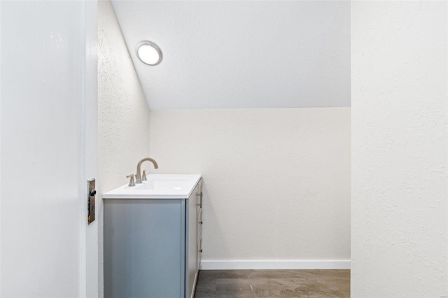 bathroom featuring hardwood / wood-style floors, vanity, and vaulted ceiling