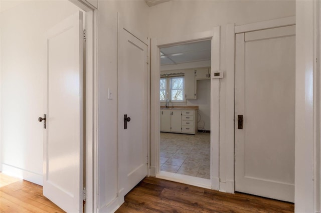 corridor with hardwood / wood-style floors and sink