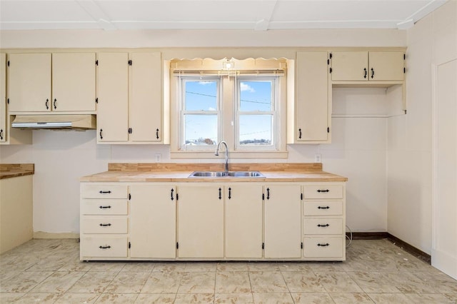 kitchen with cream cabinetry, butcher block counters, and sink