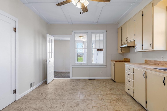 kitchen featuring ceiling fan and cream cabinets