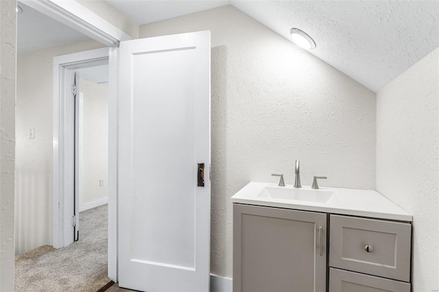 bathroom featuring a textured ceiling, vanity, and vaulted ceiling