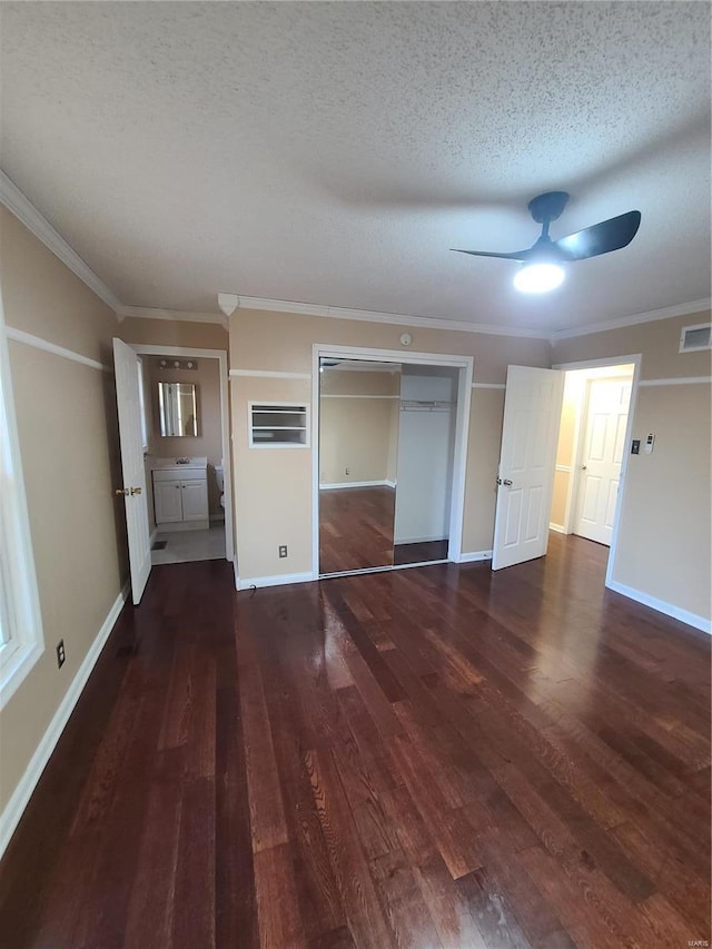 unfurnished bedroom with ceiling fan, dark wood-type flooring, crown molding, a textured ceiling, and a closet