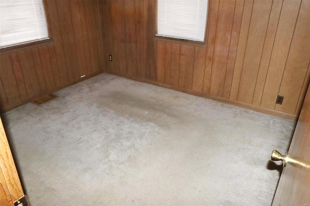 unfurnished room with wood walls and light colored carpet