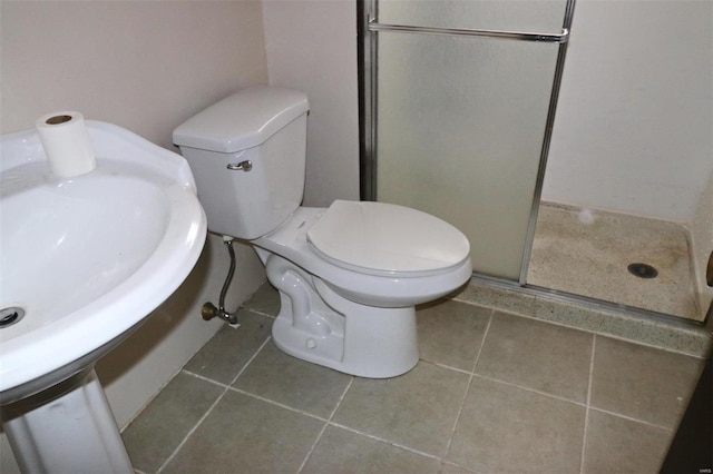 bathroom with tile patterned floors, sink, a shower with door, and toilet