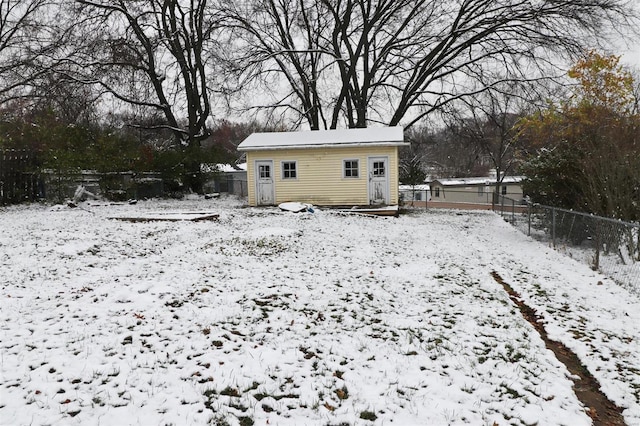 snow covered back of property with an outbuilding