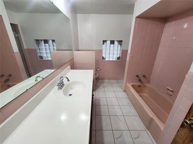 full bathroom featuring vanity, toilet, tile walls, and tiled shower / bath combo