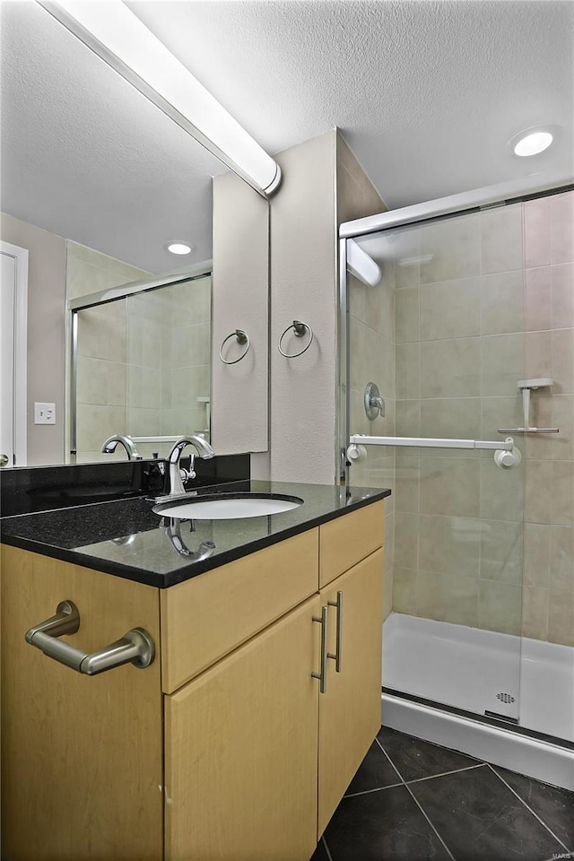 bathroom featuring tile patterned flooring, vanity, a shower with shower door, and a textured ceiling