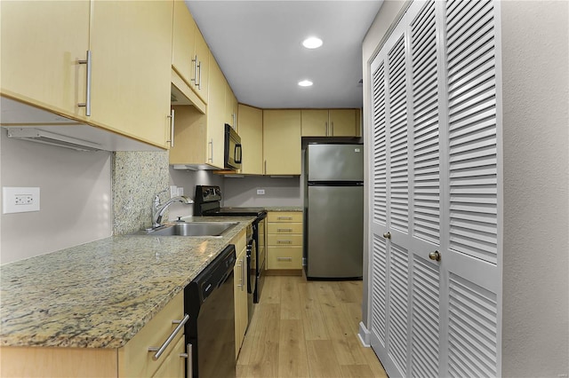 kitchen with backsplash, light stone counters, sink, black appliances, and light hardwood / wood-style floors