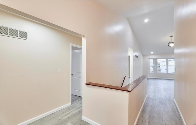 hall with baseboards, visible vents, an upstairs landing, light wood-type flooring, and high vaulted ceiling