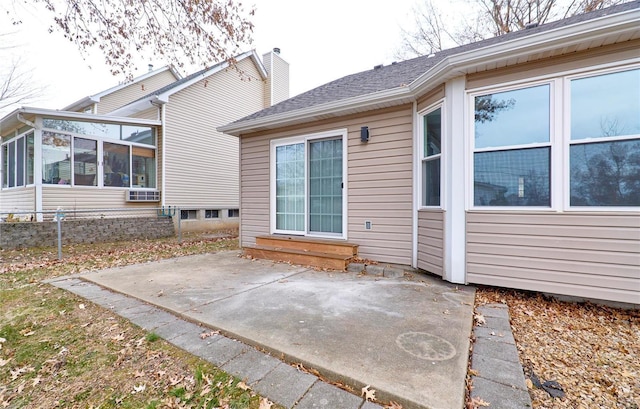 back of house with entry steps, a chimney, a patio area, and a sunroom