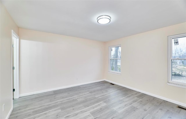 unfurnished room featuring light wood-type flooring, baseboards, and visible vents