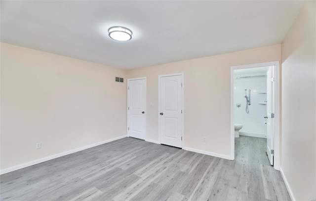 unfurnished bedroom with light wood finished floors, ensuite bath, visible vents, and baseboards