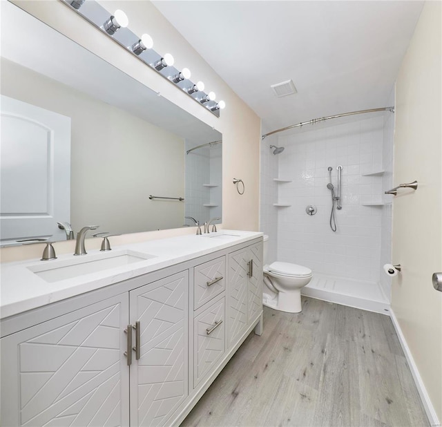 full bathroom with a stall shower, visible vents, a sink, and wood finished floors