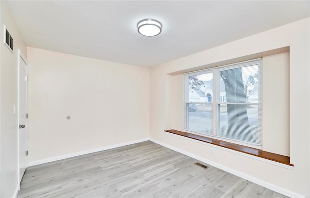 unfurnished room featuring baseboards, visible vents, and light wood finished floors