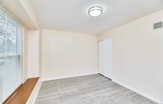 empty room with visible vents, light wood-style flooring, and baseboards