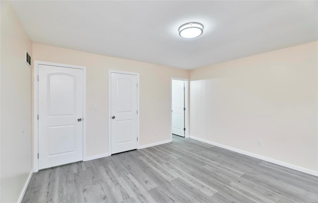 unfurnished bedroom with light wood-type flooring, visible vents, and baseboards