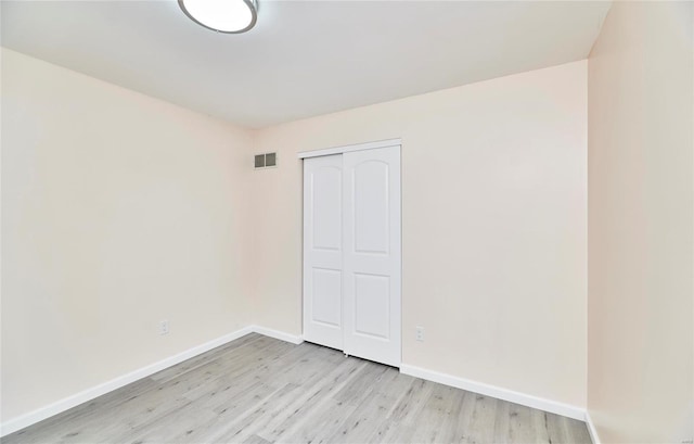 unfurnished bedroom with baseboards, a closet, visible vents, and light wood-style floors