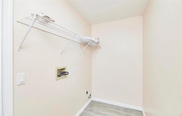 clothes washing area with baseboards, laundry area, washer hookup, and light wood-style floors