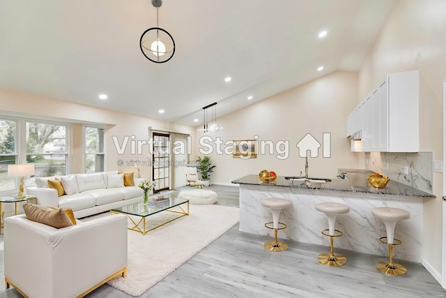 living room with light wood finished floors, baseboards, high vaulted ceiling, and recessed lighting